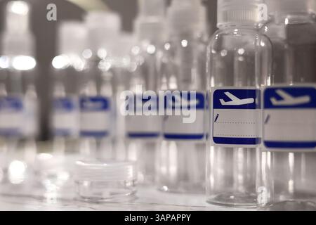 Small, transparent, plastic liquid bottles for plane traveling. Blank label with blue plane icon. Stock Photo