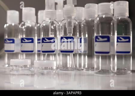 Small, transparent, plastic liquid bottles for plane traveling. Blank label with blue plane icon. Stock Photo