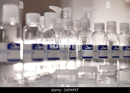 Small, transparent, plastic liquid bottles for plane traveling. Blank label with blue plane icon. Stock Photo