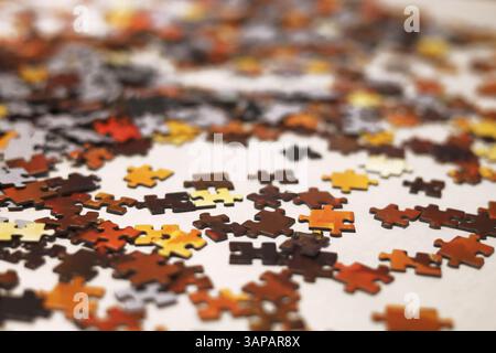 Red, orange, yellow, brown and black jigsaw puzzles scattered on the white surface Stock Photo