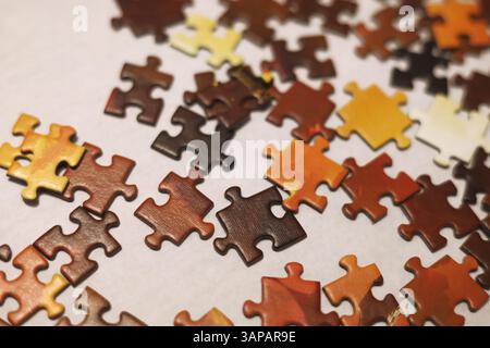 Red, orange, yellow, brown and black jigsaw puzzles scattered on the white surface Stock Photo