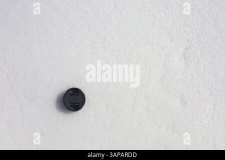 Camera lens plastic cover lying on the fresh snow surface Stock Photo