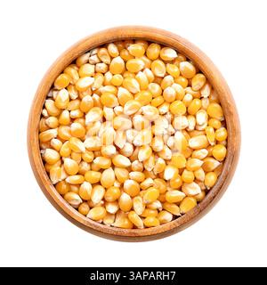 Unpopped popcorn kernels in wooden bowl. Seeds of Zea mays variety everta, rounded at the top, which expand and puffs up, when heated. Snack food. Stock Photo