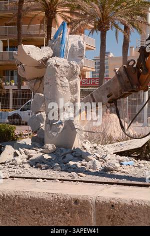 Construction workers using JCB machines to remove heavy concrete light pillars on the promenade of the Bay of Palma at Les Meravelles, Mallorca, Spain Stock Photo