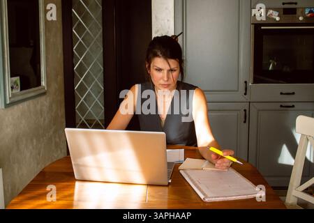 Young woman freelancer typing something on laptop sitting at home. Remote business meeting online Stock Photo