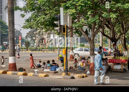 People and street vendors resting on the pavement with Flora Fountain visible in the background at Hutatma Chowk in Mumbai, India. Stock Photo