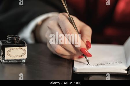 Notebook, pen and retro inkwell in the hands of a writer Stock Photo