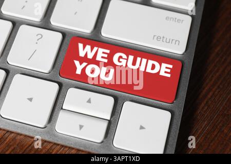 Red button with text We Guide You on computer keyboard, closeup Stock Photo