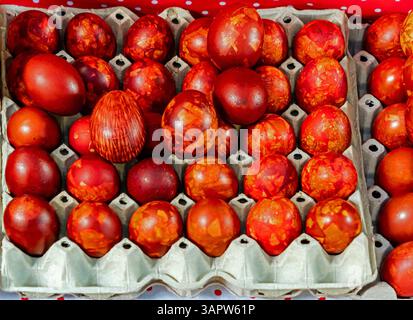 Red coloured cooked Easter chicken eggs sold outside on market during festive period Stock Photo