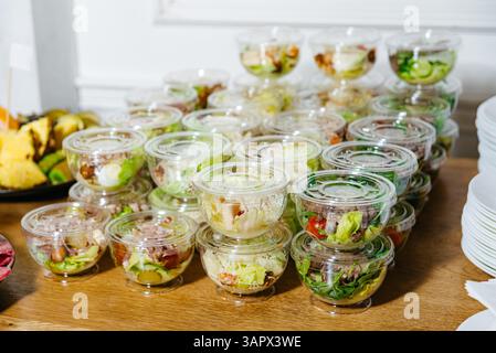 Multiple clear plastic salad bowls filled with fresh vegetables, neatly stacked for easy serving at a catered event or buffet. Stock Photo