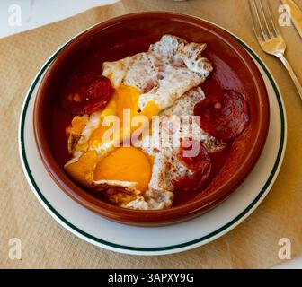 Fried eggs with chorizo and tomato paste in pan close up Stock Photo