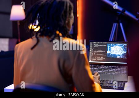 Data scientist using laptop in home office, updating artificial intelligence machine learning algorithms, writing code. Teleworking IT specialist in apartment office uses programming to upgrade AI Stock Photo