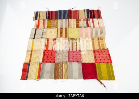A multi-colored silk doll quilt top, showcasing intricate stitching and a vibrant design. The quilt top is made from silk, providing a soft and delicate texture suitable for a doll-sized quilt. It reflects 19th-century craftsmanship and the artistry of quilt making in miniature form. Stock Photo