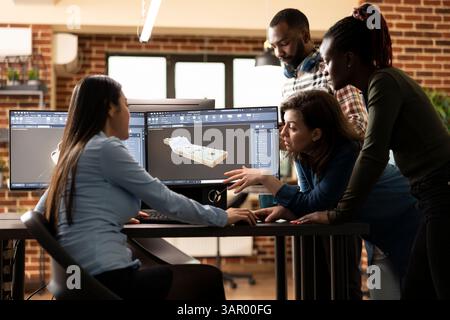 Multiethnic team of digital engineers collaborating with asian 3D artist to resolve a geometry challenge. Diverse experts working together at office desk, discussing and enhancing a virtual assets. Stock Photo