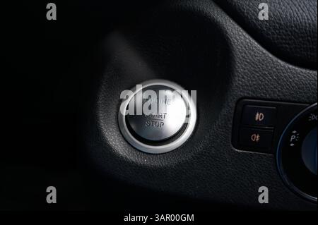 A car's start button is shown in a close up. The button is silver and has the word "start" on it Stock Photo