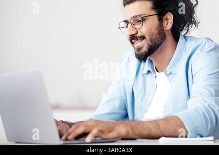 Busy Indian IT Manager Guy Working On Laptop At Workplace In Office Stock Photo