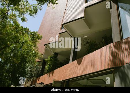 Madrid, Spain 1 June 2023 An architectural building with a unique stone facade, with plants on the balconies and green trees in the front Urban street Stock Photo