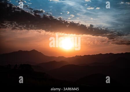 Sunset in Brazil Across Mountain Silhouettes with Cloud Formation Resembling an Eye in the Sky Stock Photo