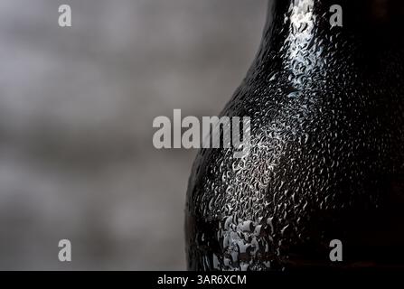 Close up view of water drops on black bottle against grey background Stock Photo