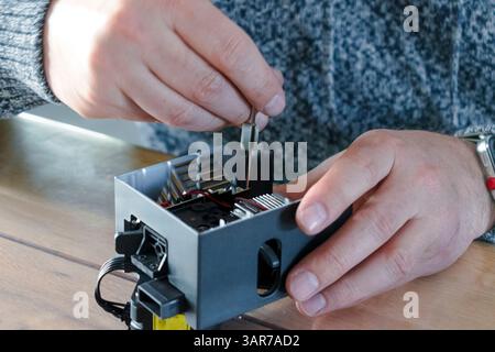 Man dismantling an electrical component for repair Stock Photo - Alamy