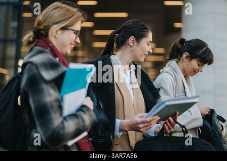 Three businesswomen collaborating outdoors while reviewing documents and sharing ideas Stock Photo
