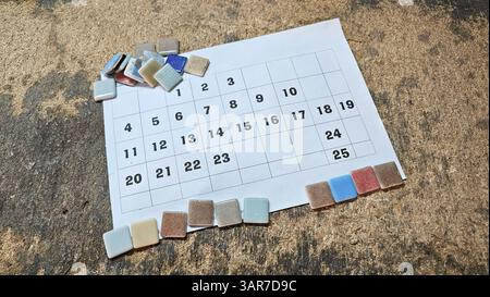 Calendar and ceramic mosaic tiles arranged on a workbench, suggesting a tiler organizing materials for a project Stock Photo