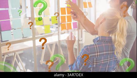 Image of green and red question marks over business people looking at memo notes Stock Photo