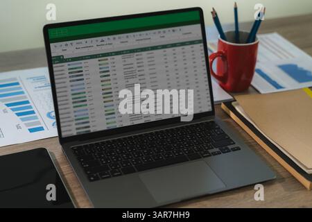 A professional analyst uses digital software and spreadsheets to present finance data, charts, and reports in a modern workplace. Stock Photo