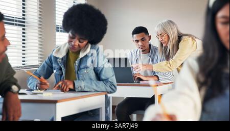 Classroom, teacher and helping student with laptop for online lesson, education support or assignment assistance. Educator, boy and high school app Stock Photo