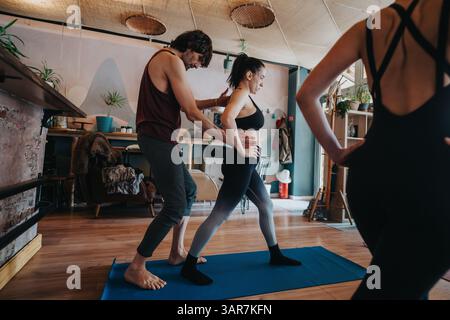 Instructor guiding a yoga class with participants practicing various poses in a peaceful studio environment Stock Photo