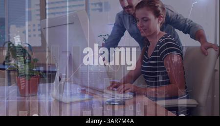 Image of diverse data and clock over caucasian female and male colleagues working at computer Stock Photo