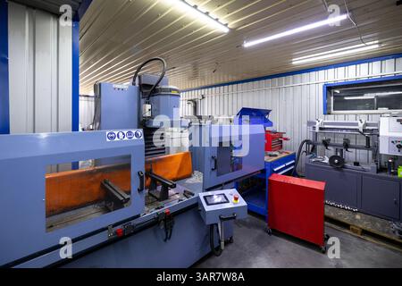 An industrial CNC milling machine is situated within an auto repair shop that specializes in comprehensive repairs of cargo vehicles. Stock Photo