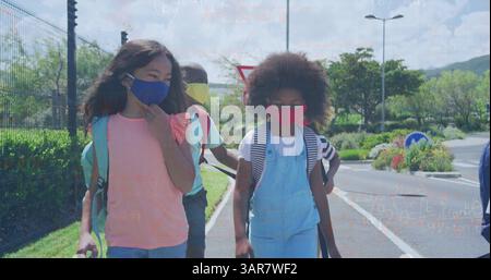 Image of mathematical equations over diverse schoolchildren wearing face masks Stock Photo