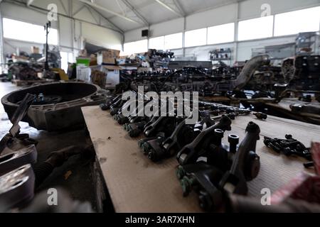 Various disassembled engine components are neatly arranged on a workbench in a spacious repair shop or warehouse filled with other engine parts and eq Stock Photo