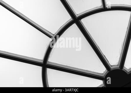 Monochrome close-up of a geometric window detail featuring intersecting lines and shapes, creating an abstract composition. The minimalistic contrast Stock Photo