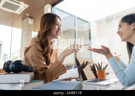 Study Session and Friendship. Two university students engage in a lively discussion while studying together. Stock Photo