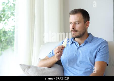 Man eating cheese looking away sitting on a couch at home Stock Photo