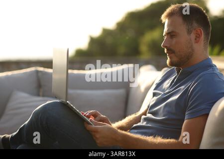 Serious man using laptop sitting in a terrace at home or hotel Stock Photo