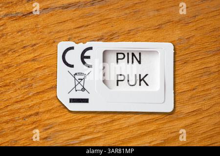 Bavaria, Germany - April 16, 2025: A small PIN/PUK card for mobile devices on a wooden table - important security carrier for unlocking SIM cards when the PIN code is blocked. *** Eine kleine PIN/PUK-Karte für Mobilgeräte auf einem Holztisch wichtiger Sicherheitsträger zum Entsperren von SIM-Karten bei gesperrtem PIN-Code. Stock Photo