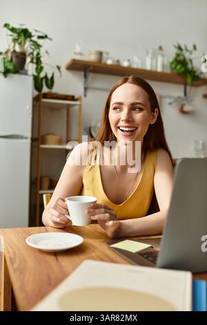 A joyful young woman sips her coffee, surrounded by greenery in a relaxed kitchen atmosphere. Stock Photo