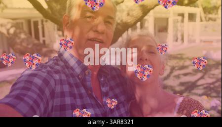 Image of heart icons over happy senior caucasian couple in garden Stock Photo