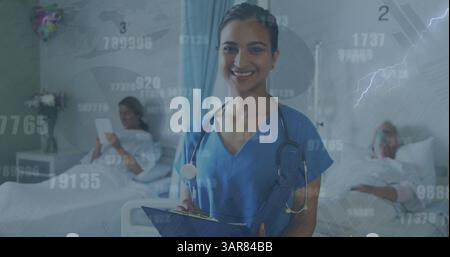 Image of numbers and data processing over biracial female doctor with patients Stock Photo