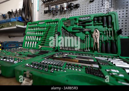 An open 216-piece flank socket wrench set is displayed on a workbench in a workshop, with various other tools organized on a pegboard in the backgroun Stock Photo