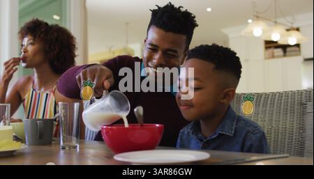 Image of pineapples over happy african american parents and son having breakfast at home Stock Photo