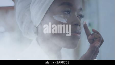 Image of african american woman using cream on face over light spots Stock Photo