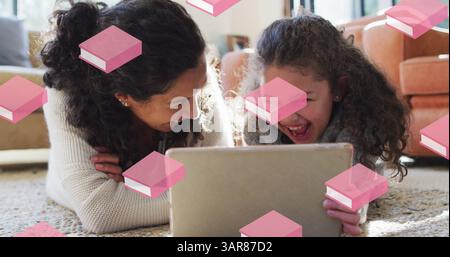 Pink book icons in seamless motion against caucasian mother and daughter using digital tablet Stock Photo