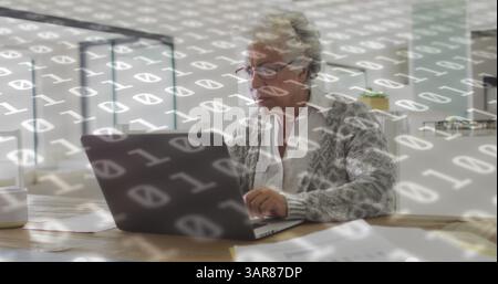 Composite image of binary coding data processing against african american senior woman using laptop Stock Photo