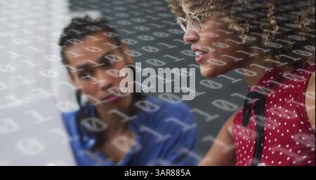 Image of binary coding over diverse business people using laptop Stock Photo