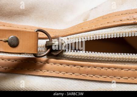 Zipper on old dirty white cosmetic bag with brown leather inserts, zipper on bag Stock Photo