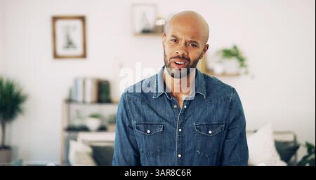 Home, man and portrait with expression for confused, misunderstanding and puzzled with news. House, lounge and African male person with emoji reaction Stock Photo